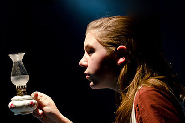 a young girl holding an oil lamp in the dark