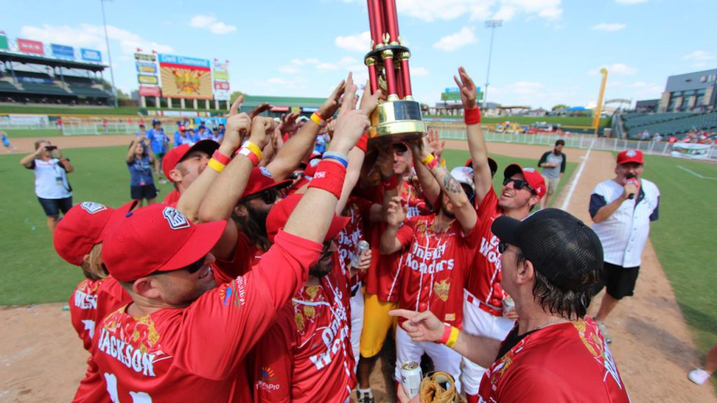 Softball players hoisting a trophy up at the Reckless Kelly Celebrity Softball Jam