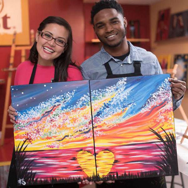 a young woman and man holding a painting of a colorful water scene