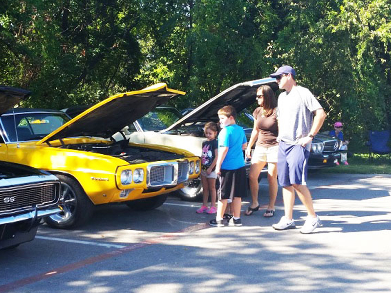 family looking at cars at a car show