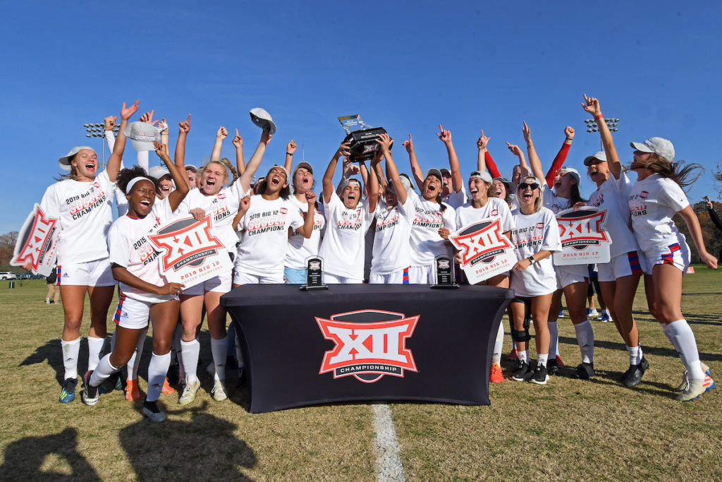 Big 12 Women's Soccer Champions holding up trophy and signs