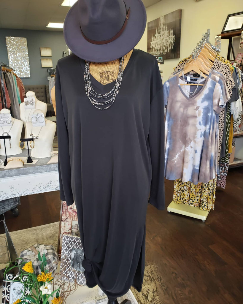 A photo of a fashion display with a hat, necklace and black dress. 