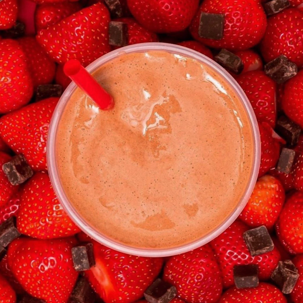 Photo of strawberries and chocolate chunks and a smoothie in the middle. 