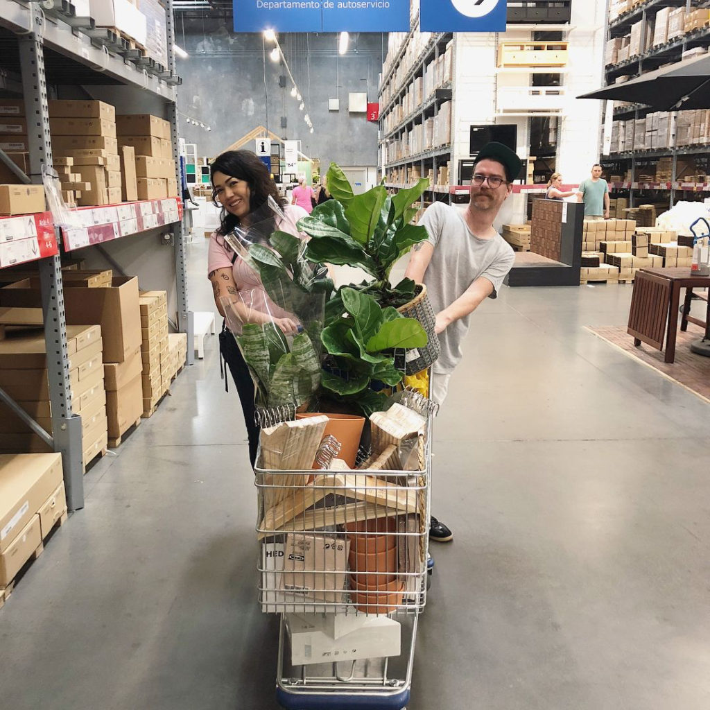 Couple shopping at Ikea with their cart full. 