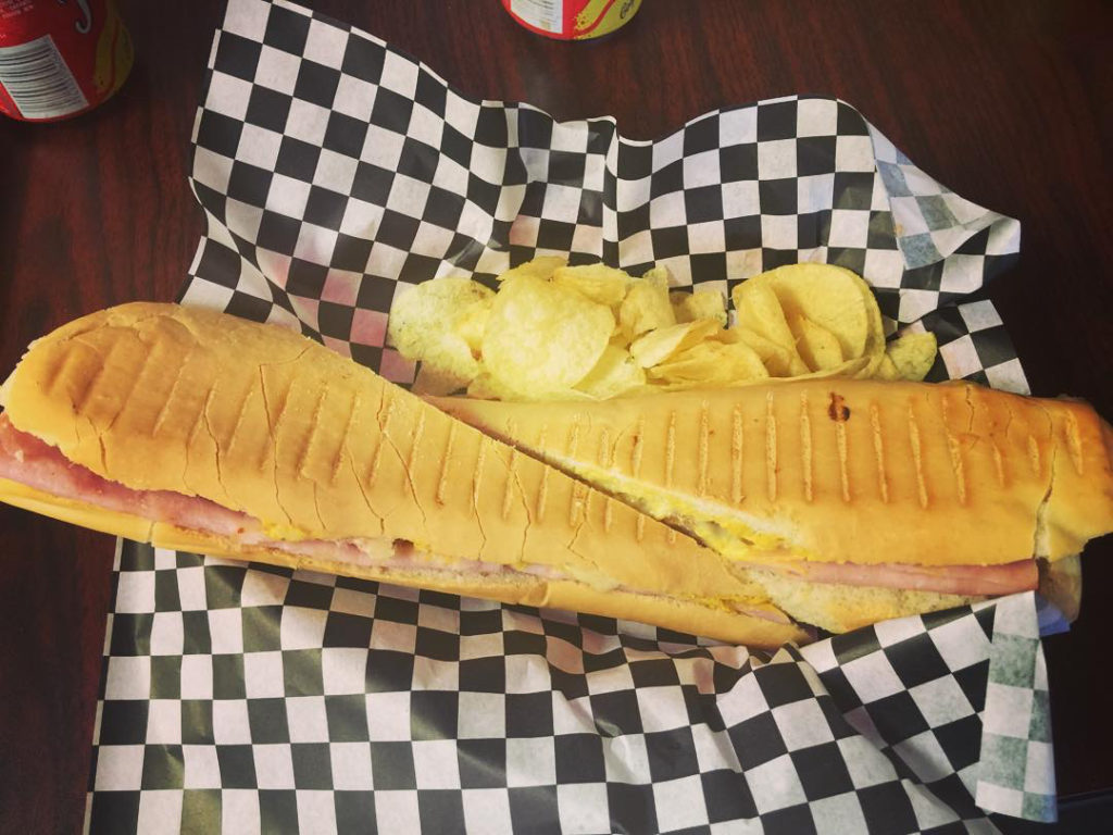 Picture of a large Cuban sandwich and chips on the side. 