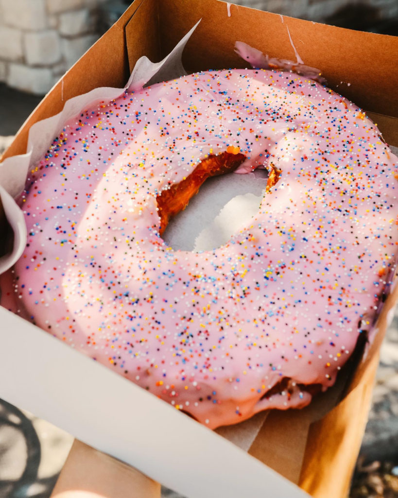 Giant donut with pink frosting and multi-color sprinkles from Round Rock Donut.