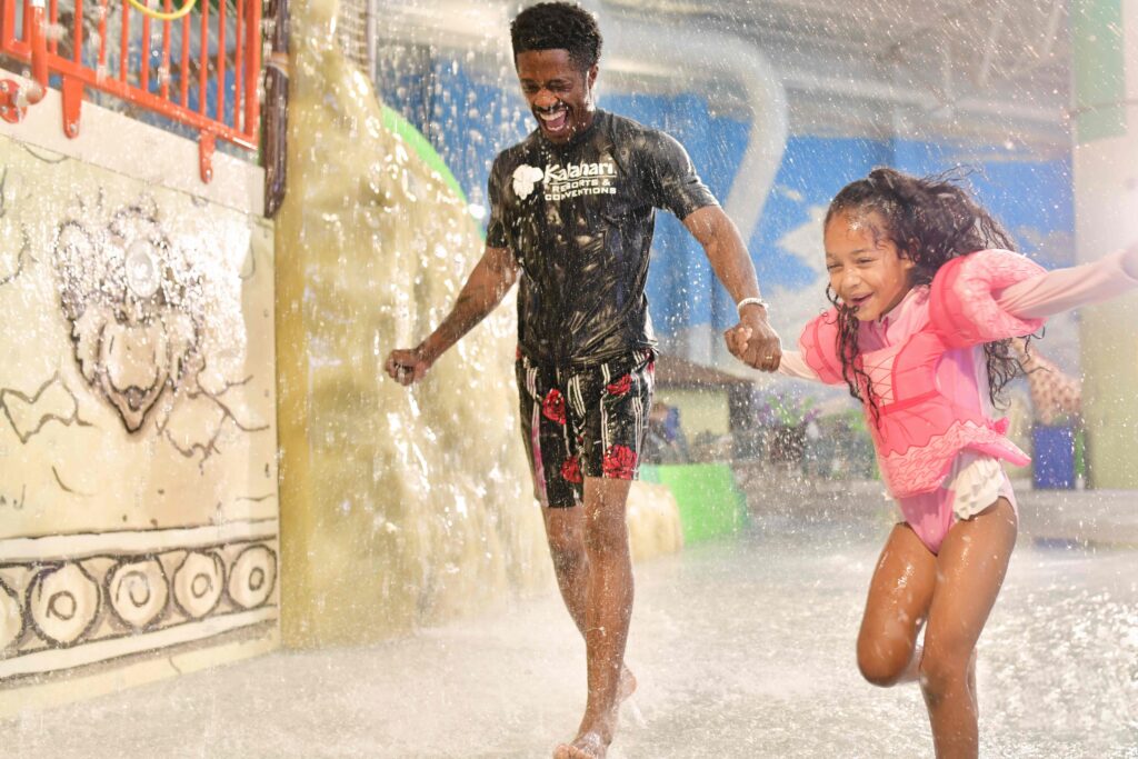 Picture of a father and daughter running through the water. 