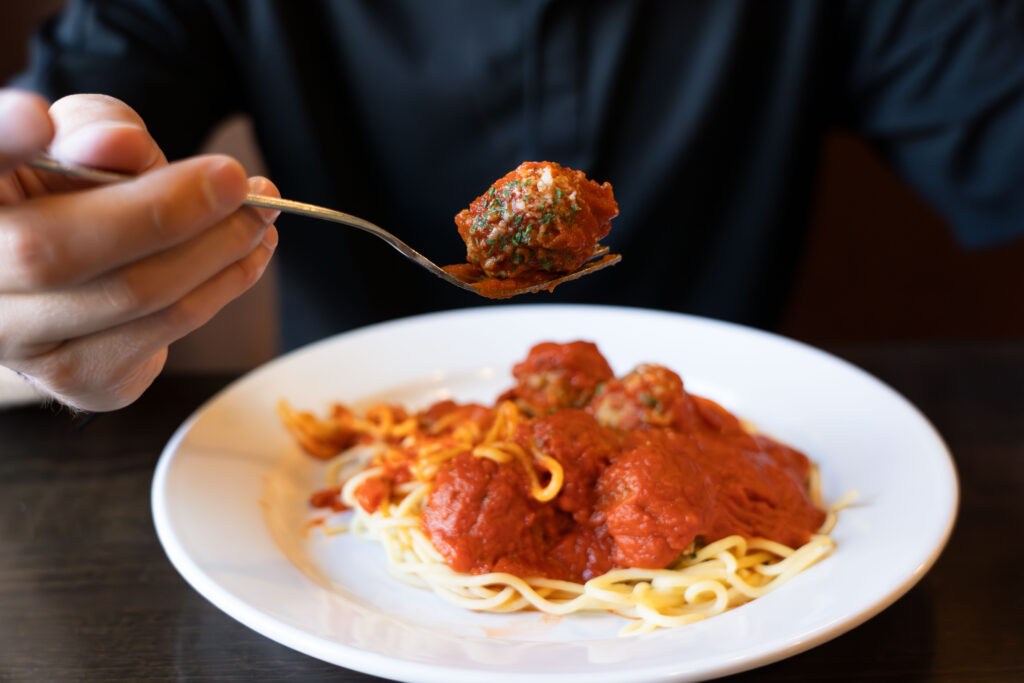 Spaghetti and meatballs at Palermos, with a fork lifting a sauced meatball.