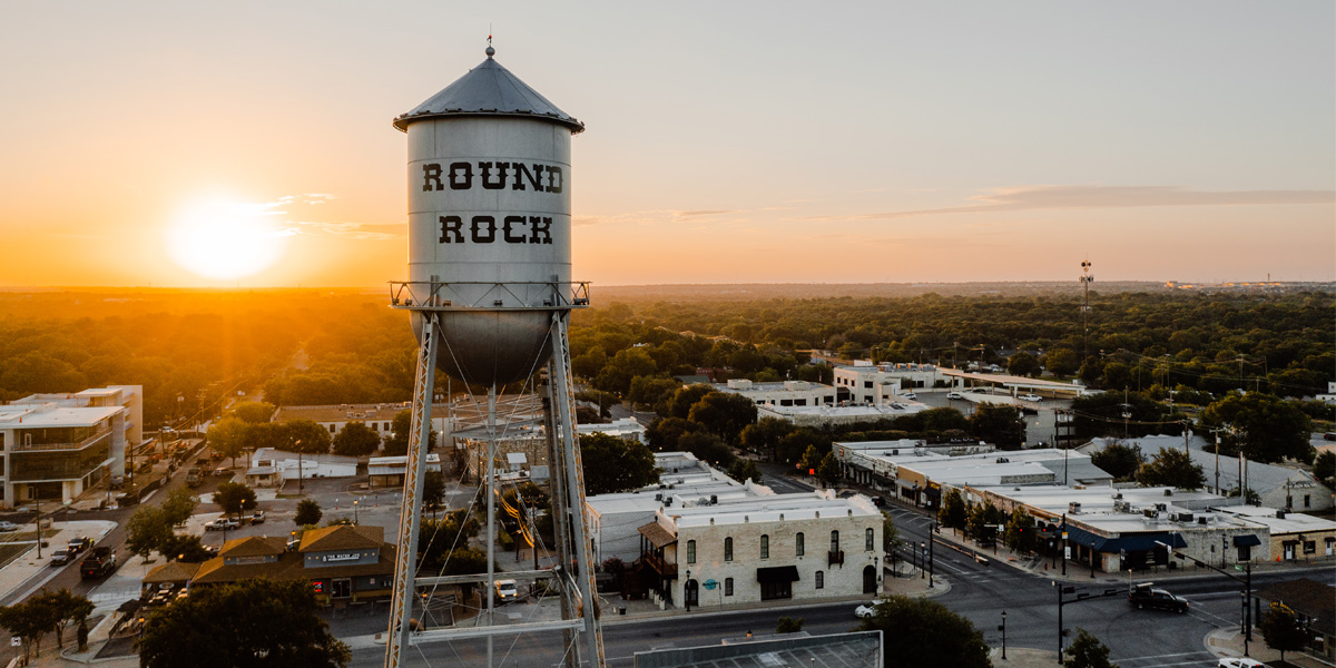 The Round Rock water tower standing in front of a sunset 