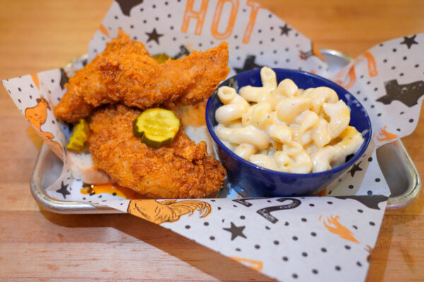 Tumble 22 hot chicken tenders with pickles served beside a bowl of macaroni and cheese.