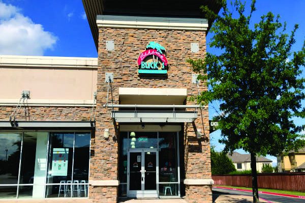 Exterior of a Bahama Buck's shop with stone pillars, a blue logo, and a small tree in front.