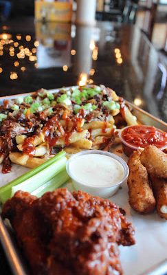Appetizer spread with buffalo wings, mozzarella sticks, and loaded fries at Tejas Meat Supply.