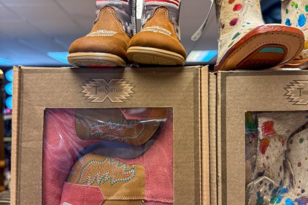 Children's cowboy boots with American flags and colorful patterns on display in boxes and on a shelf.